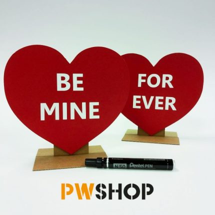 Two red 'Sweetheart Stand' popup decorations stood next to each other. 'Be Mine' written on one and 'Forever' on the other. Black sharpie pen laying next to them. PW Shop logo is also visible.