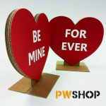 Two red 'Sweetheart Stand' decorations stood next to each other. One has 'Be Mine' written on it. The other has 'Forever' written on it. PW Shop logo is also visible.
