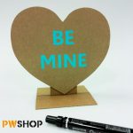 Plain cardboard 'Sweetheart Stand' pop up heart decoration. With 'Be Mine' written on it. Black sharpie pen is visible and the PW Shop logo is visible.